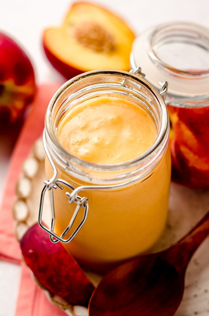 two jars filled with liquid sitting on top of a table next to an apple slice