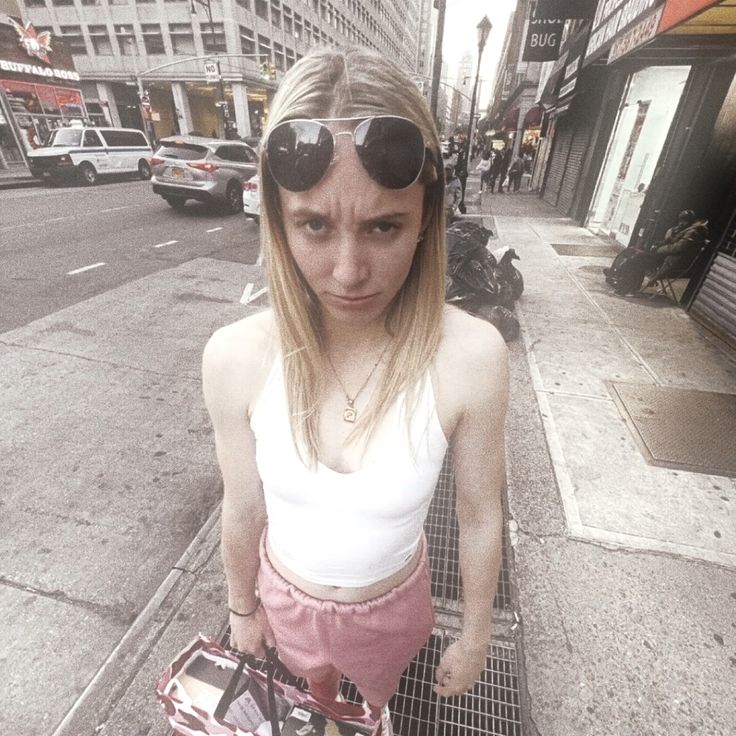 a woman with sunglasses on standing next to a shopping cart in front of a city street