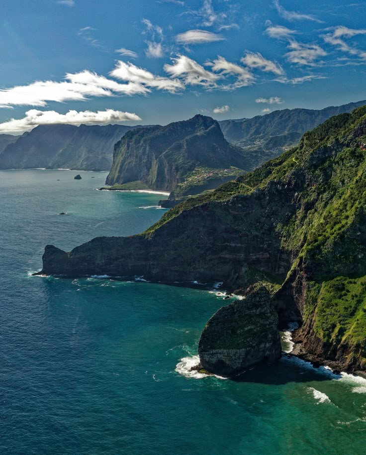 an aerial view of the ocean with mountains in the background