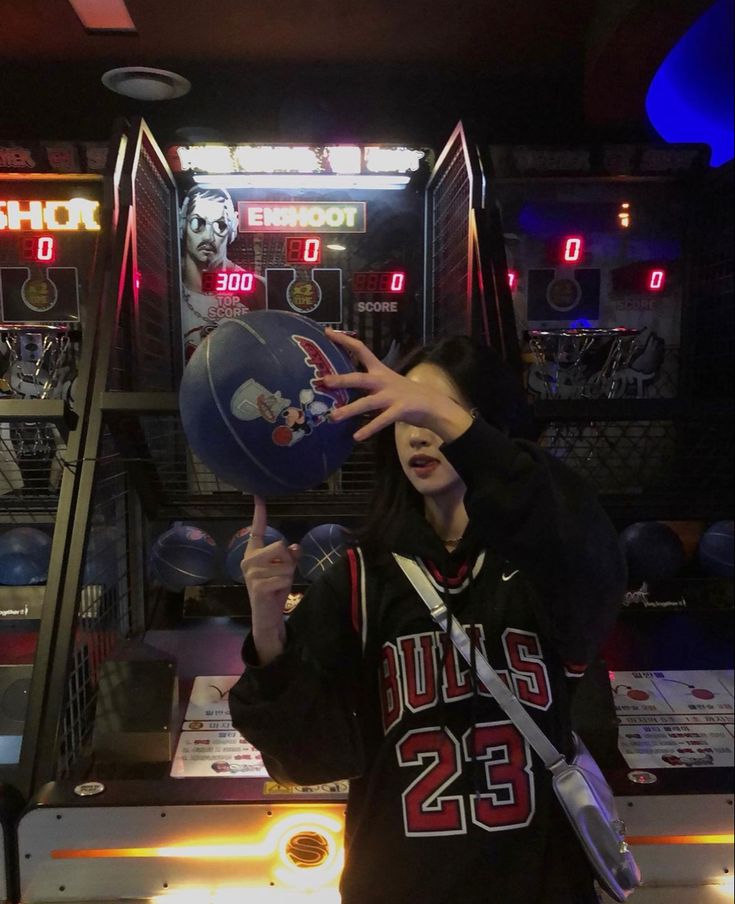 a young man holding a basketball in front of a slot machine at a game room