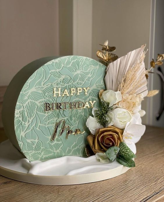 a happy birthday card with flowers and feathers on top of a wooden table in front of a door