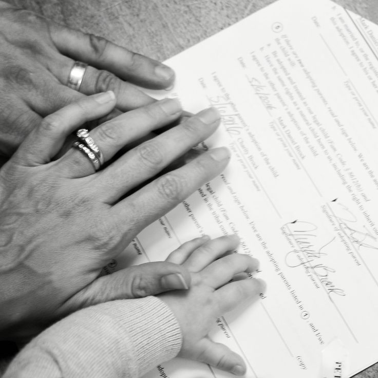 two people holding hands on top of a piece of paper