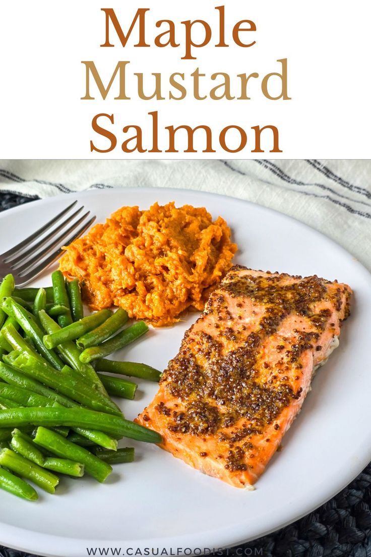 a white plate topped with salmon, green beans and mashed potatoes next to a fork