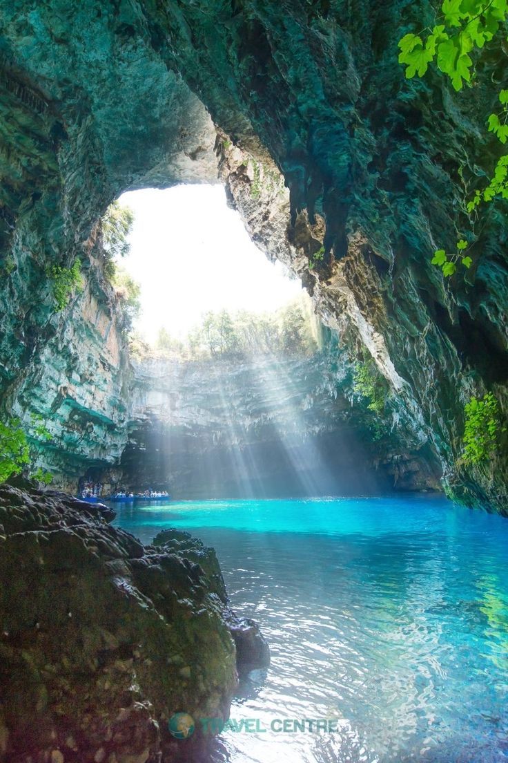 the inside of a cave with blue water and sunlight coming from it's entrance