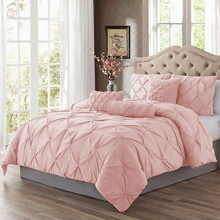 a bed with pink comforter and pillows in a room