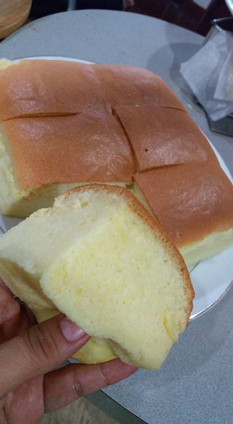 a person holding a piece of bread in their hand on a white and gray plate