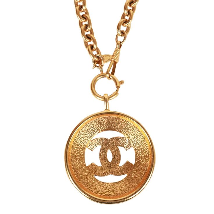 This vintage 1980's necklace features a large classic CC medallion with a sunburst design, long rolo chain and a springring/hook closure in 24K gold plated metal. Origin: France Condition: Vintage; Excellent - this necklace shows mild signs of wear, including light scratching, pitting, and some darkening near the chain links. Accompanied by: Chanel box Measurements: 16" chain, 2.25" x 2.25" pendant Gold Chain Necklace With Gold-tone Logo, Gold Chain Necklace With Logo Plaque, Gold Metal Necklaces With Gold-tone Logo Plaque, Metal Pendant Jewelry With Gold-tone Logo Plaque, Metal Pendant Necklace With Gold-tone Logo Plaque, Luxury Gold Chain Necklace With Logo Plaque, Luxury Gold Chain Necklace With Logo, Vintage Gold Necklace With Gold-tone Logo Plaque, Vintage Jewelry With Gold-tone Logo Plaque