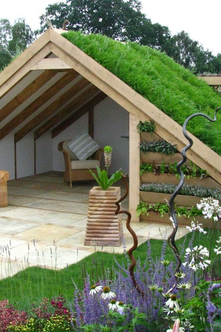 a green roof on top of a building in the middle of some flowers and plants