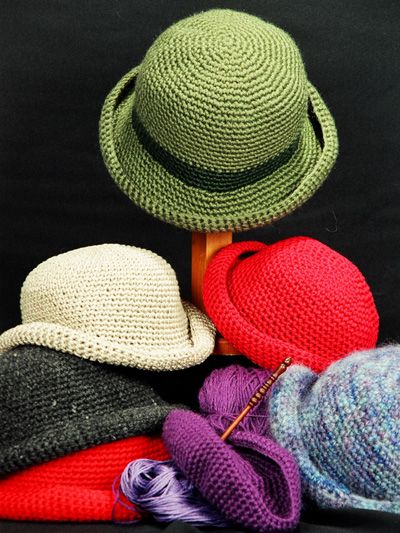 three hats are sitting next to each other on a black surface and one is crocheted