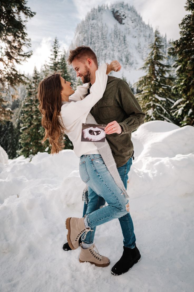 a man and woman are standing in the snow with their arms around each other as they hug