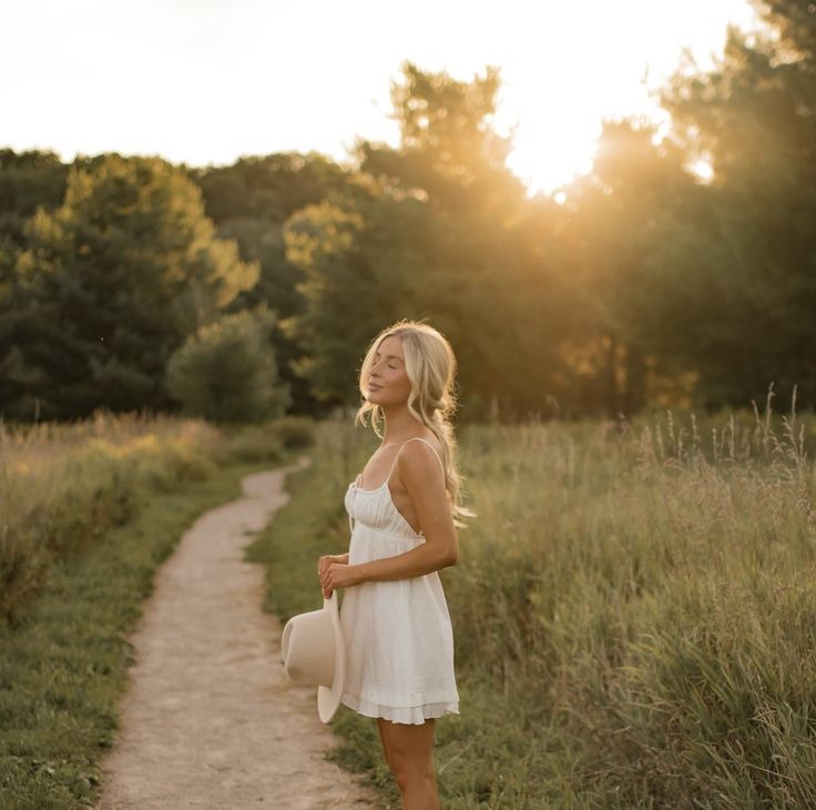 a woman in white dress standing on dirt path