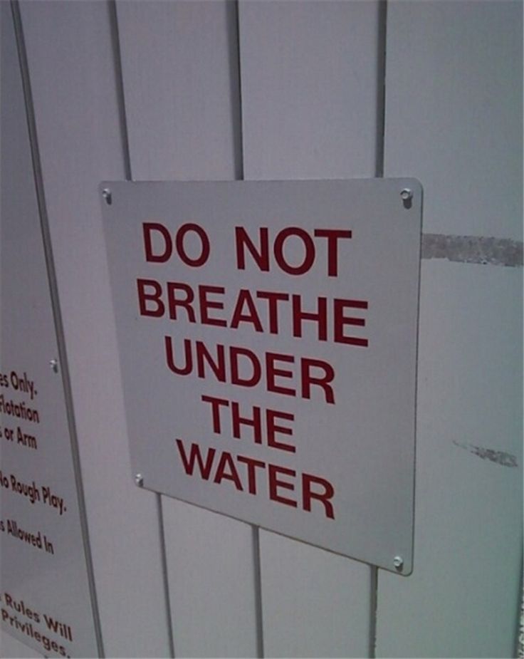 a do not breathe under the water sign attached to a white fence with red lettering