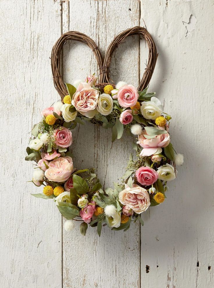 a heart shaped wreath with flowers hanging on the wall