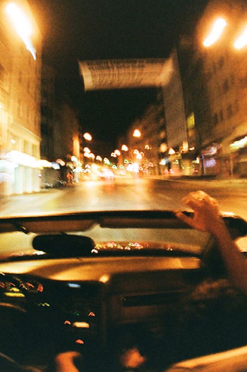 two people in a car driving down the street at night