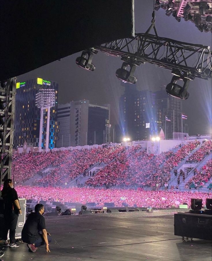 a man kneeling down in front of a stage with lots of pink flowers on it