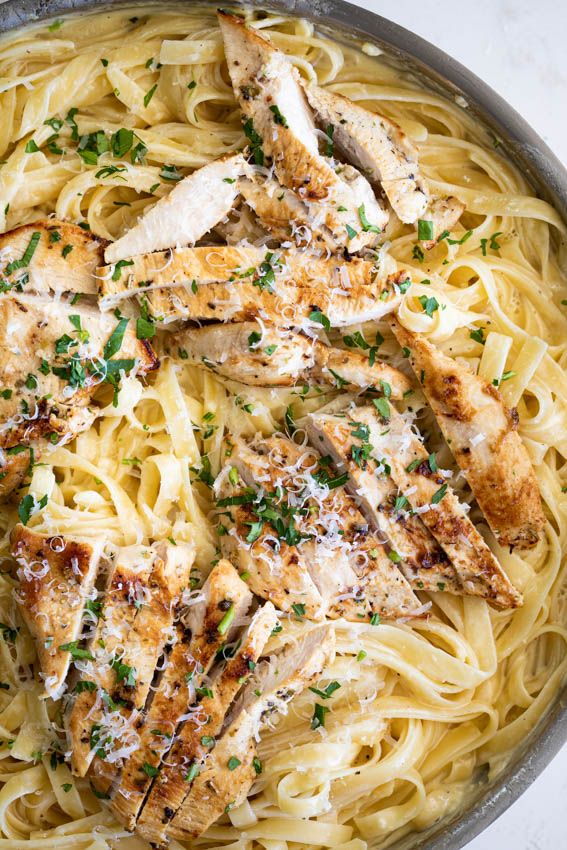 chicken and pasta in a skillet with parsley sprinkled on the top