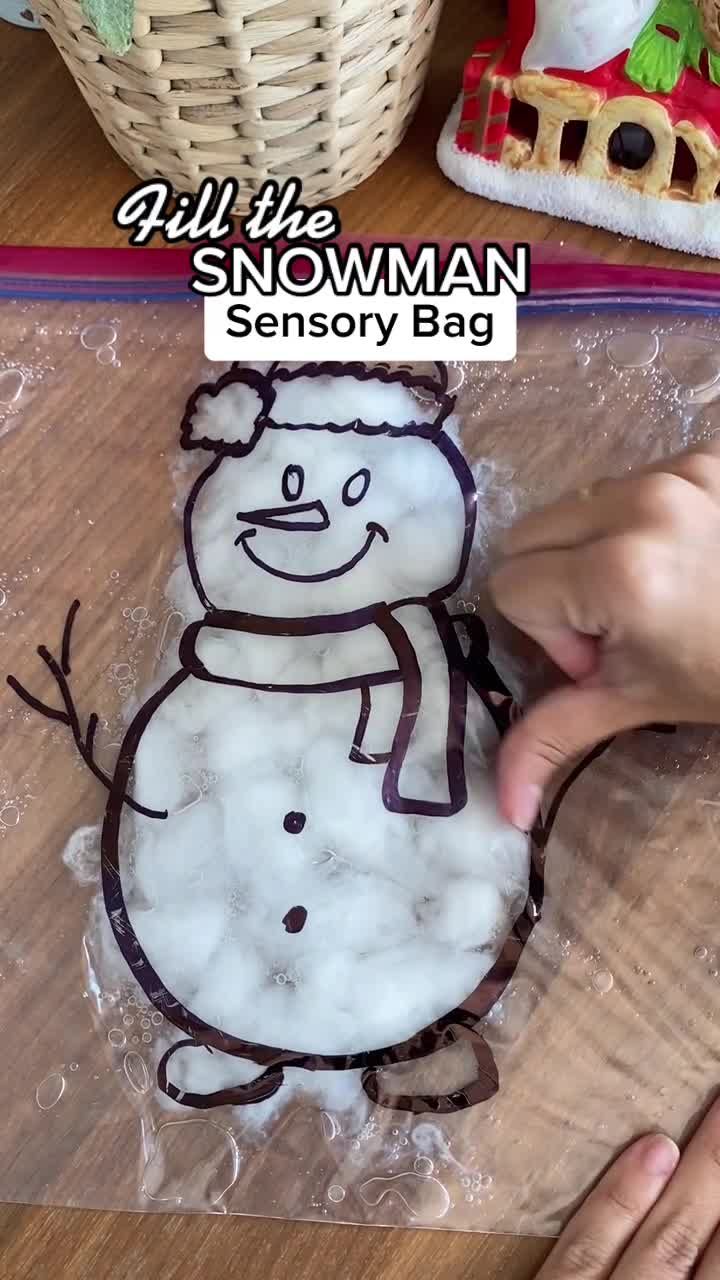 someone is making a snowman - themed cake on the table with plastic wrap around it