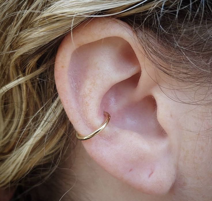 a close up of a person's ear with a gold ring on it