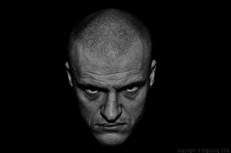 a black and white photo of a man with bald hair looking at the camera while staring into the distance