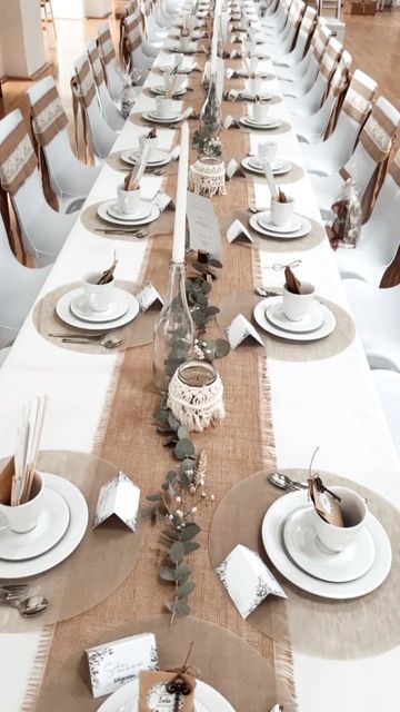 the table is set with white plates and place settings