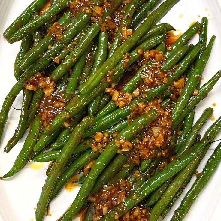 green beans with sesame seeds and seasoning on a white plate, ready to be eaten