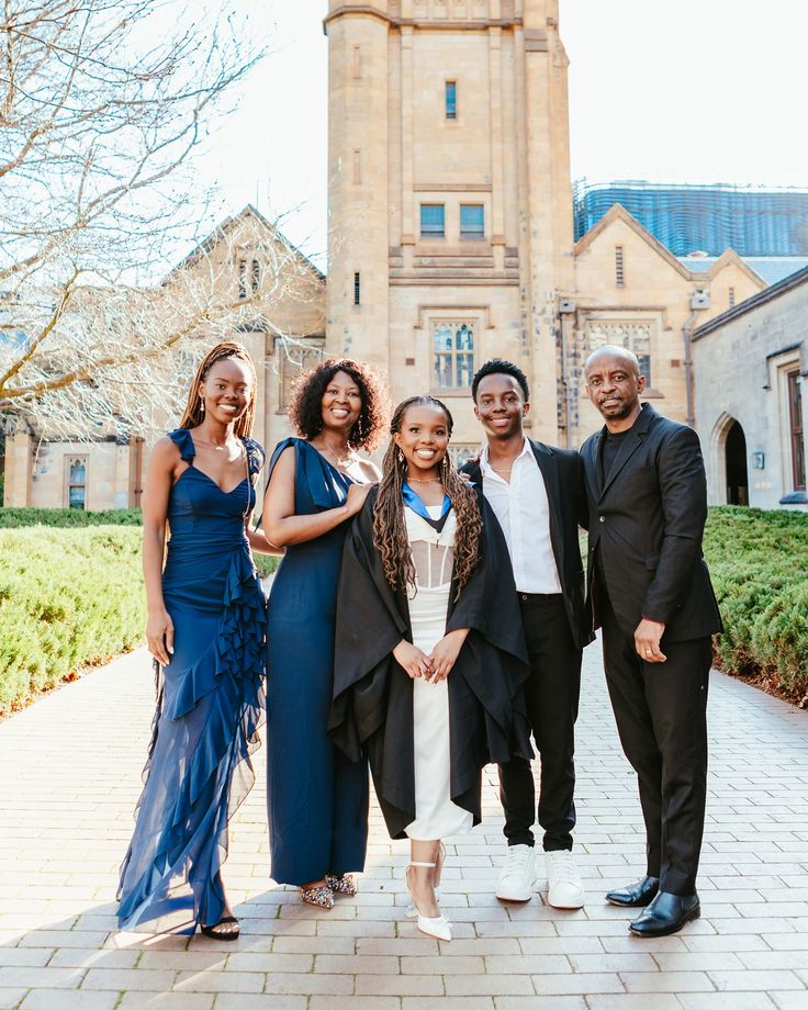 a group of people standing in front of a building with a clock tower behind them