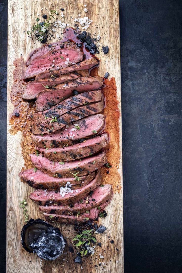 sliced steak on a cutting board with herbs