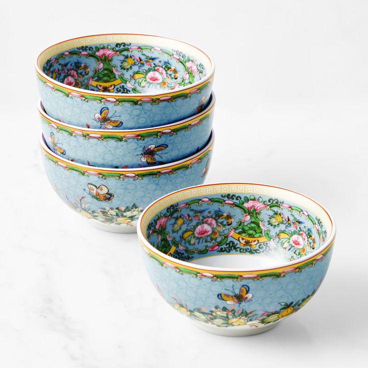 three blue bowls with flowers and butterflies on them sitting next to each other in front of a white background