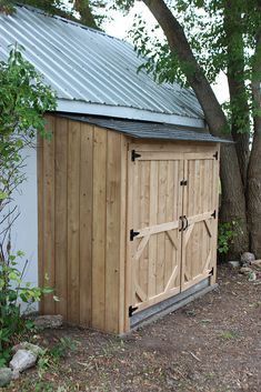 a wooden storage shed sitting next to a tree