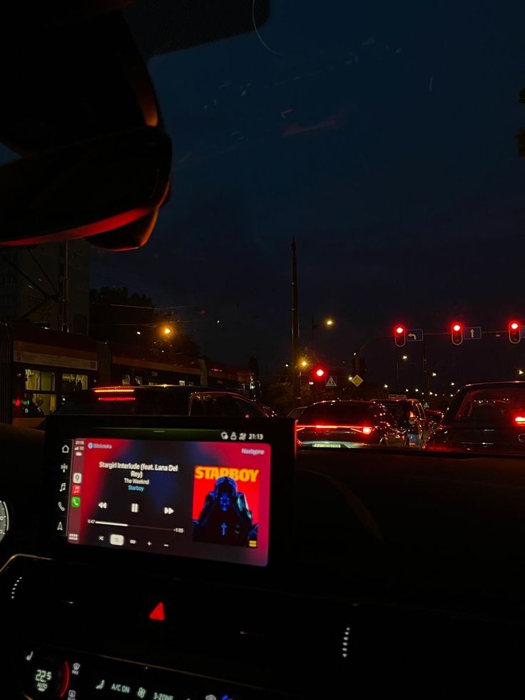 the dashboard of a car at night with traffic lights in the background and an image of a man on his cell phone