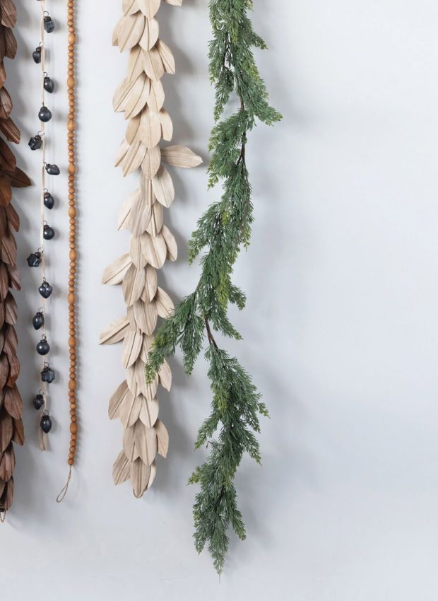 three wooden leaves hanging on a wall next to beads and necklaces in various colors