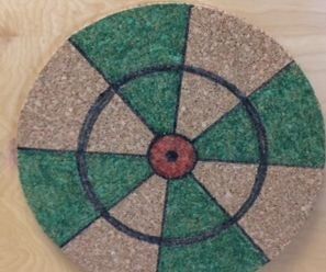 a close up of a green and white object on a wooden surface with circles painted on it