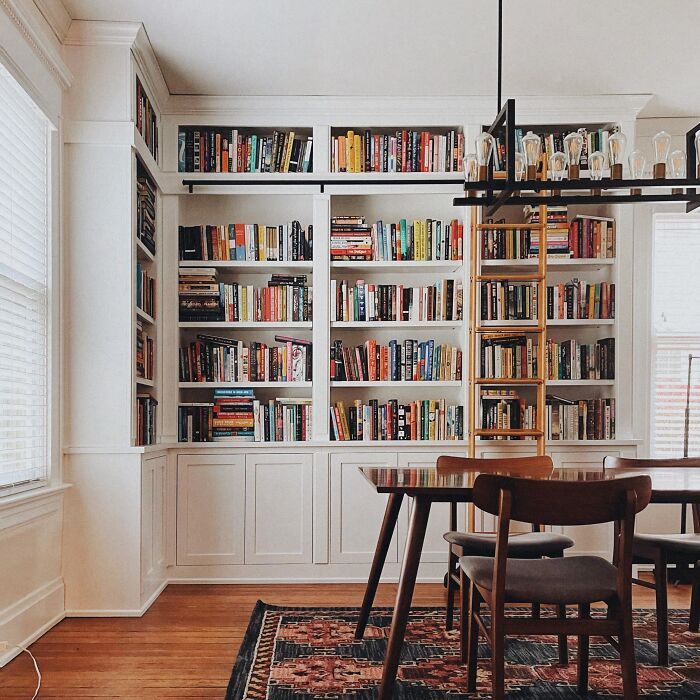 a dining room table and chairs with bookshelves in the background