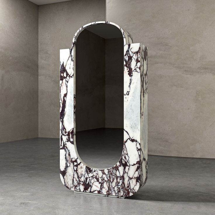 an unusual white and black marbled mirror in a room with concrete walls behind it