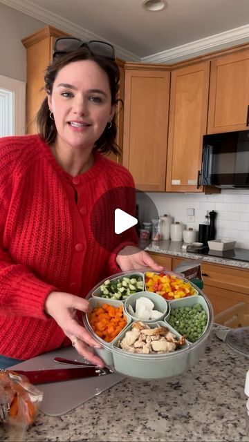 a woman in a red sweater is holding a bowl of food