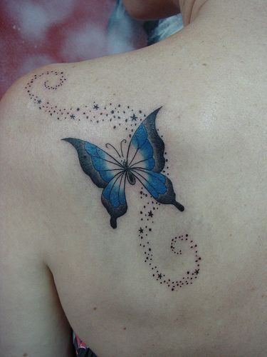 a blue butterfly tattoo on the back of a woman's shoulder