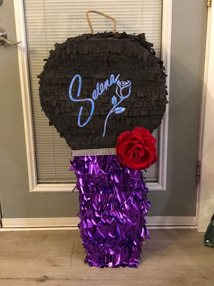 a purple and red flower sitting on top of a black sign next to a door