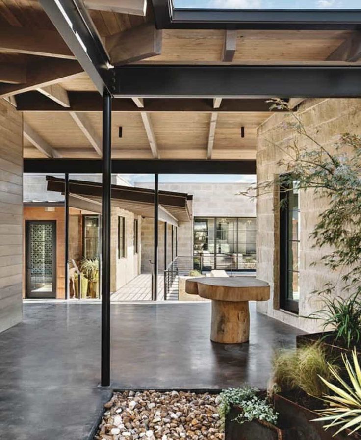 an outdoor dining area is shown in this modern house with stone walls and wood ceilinging