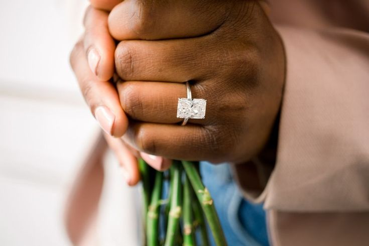 a close up of a person's hand holding a bouquet of flowers with a diamond ring on it