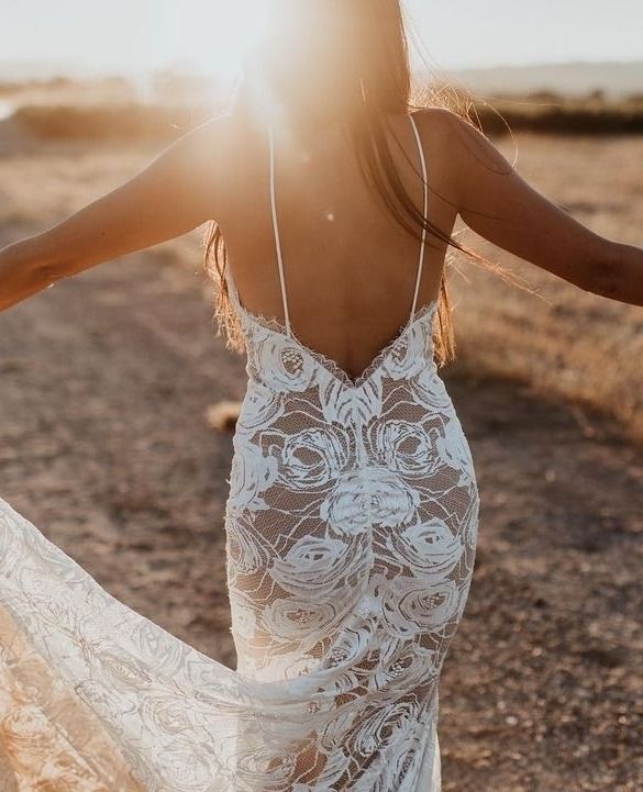 a woman in a white dress is walking through the desert with her arms spread out