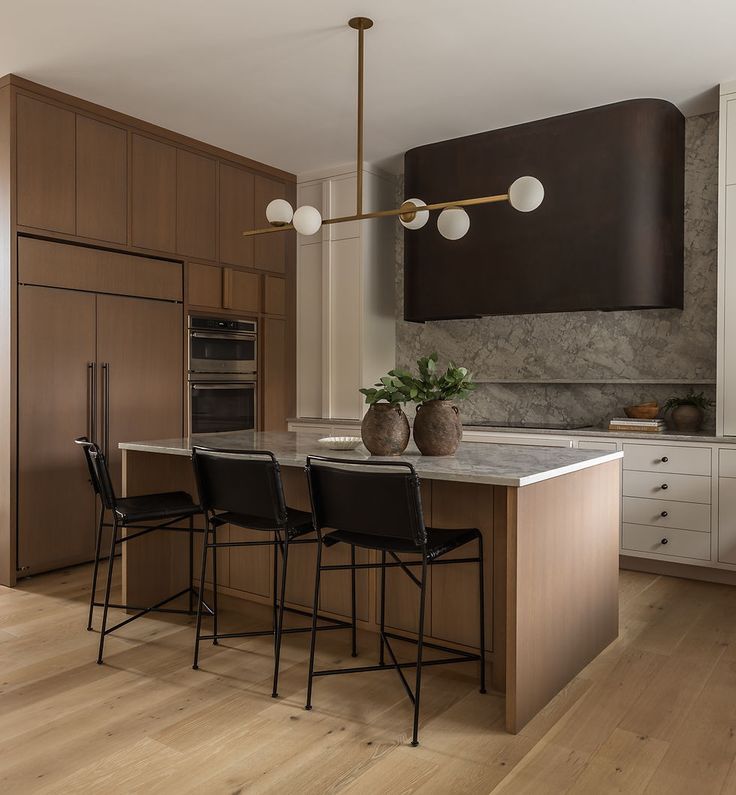 a kitchen with an island and three chairs next to the counter top in front of it