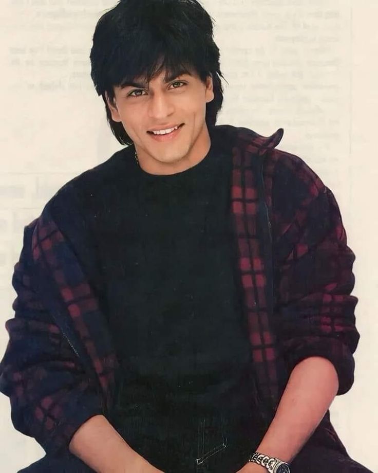 a young man with black hair sitting down