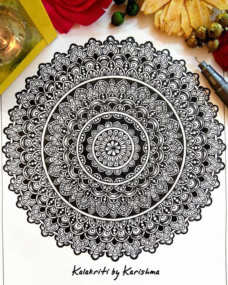 an intricate design is shown on top of a piece of paper next to some flowers