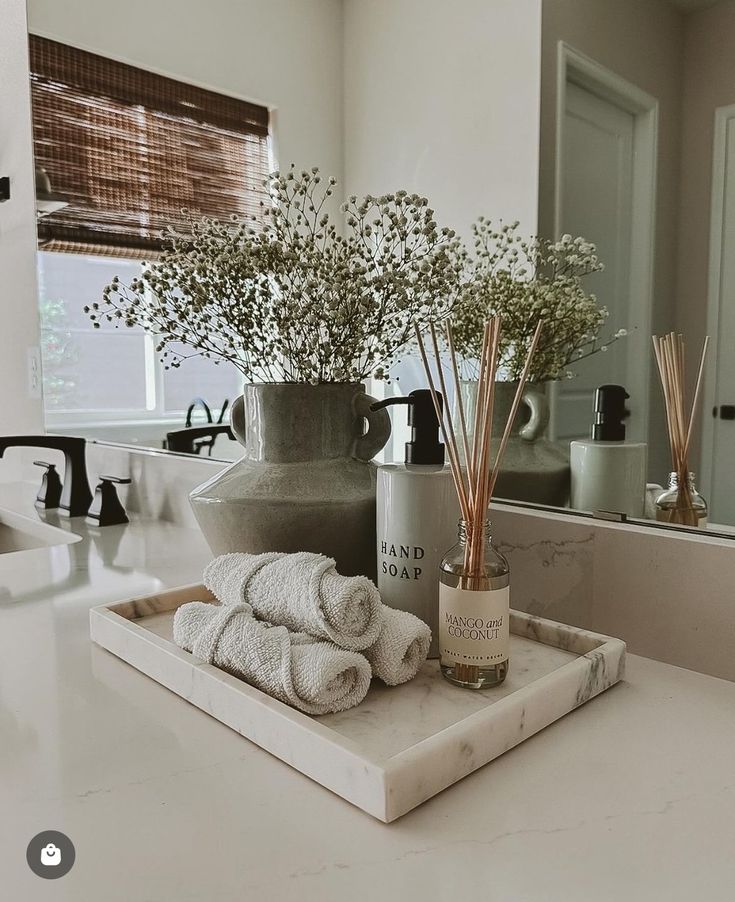 a bathroom counter topped with towels and vases filled with flowers