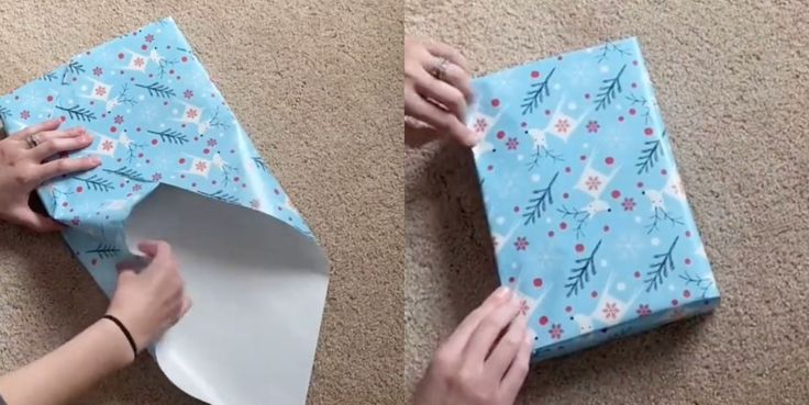 two hands wrapping a blue gift box on the floor with one hand and another person reaching for it