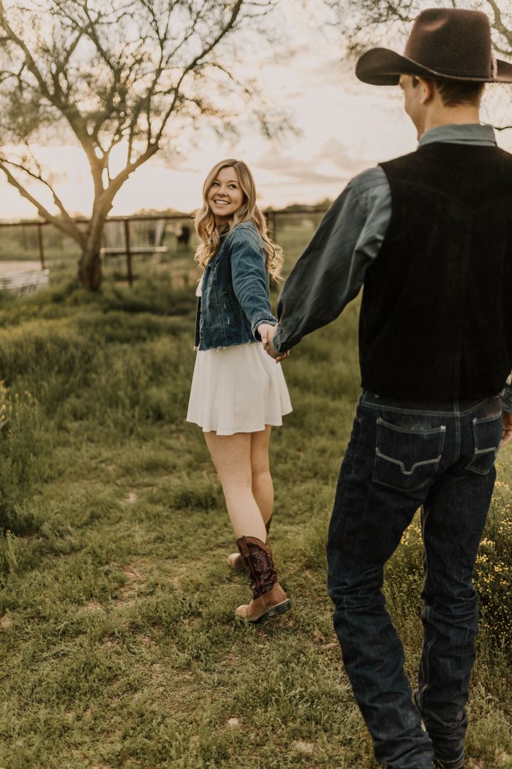 a man and woman holding hands in the grass