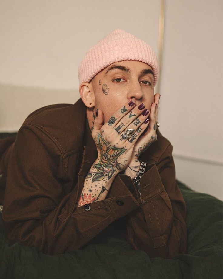 a man with tattoos on his hands covering his mouth