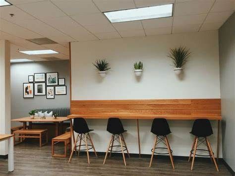 an empty office with chairs and plants on the wall, along with tables and benches