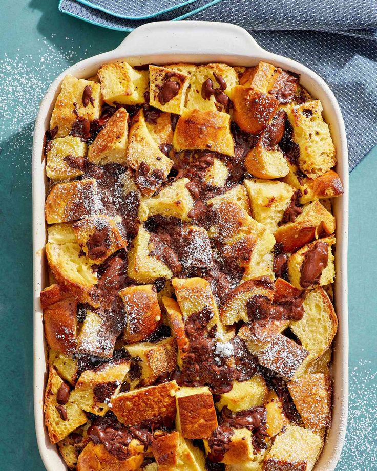 a casserole dish filled with bread and other toppings on a blue table