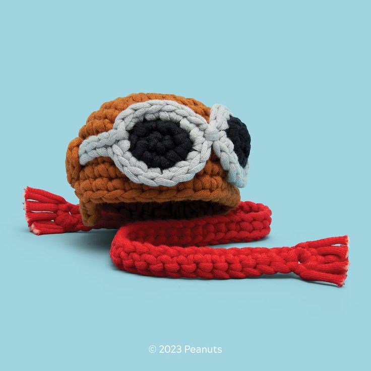 a crocheted hat with an eyeball on it and a red ribbon around the brim